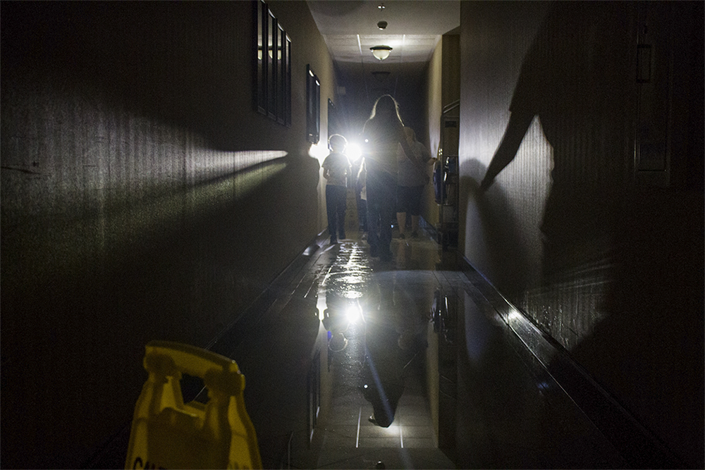 A family walks through a dark and flooded hallway at the Staybridge Suites in Wilmington after the power went out after Hurricane Florence made landfall. (Port City Daily photo/Johanna Ferebee)