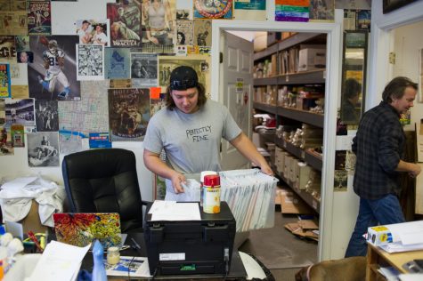 Bremen Sullivan, 19, carries files of engravings and prints as his father Kenyata walks by. (Port City Daily photo/Mark Darrough)