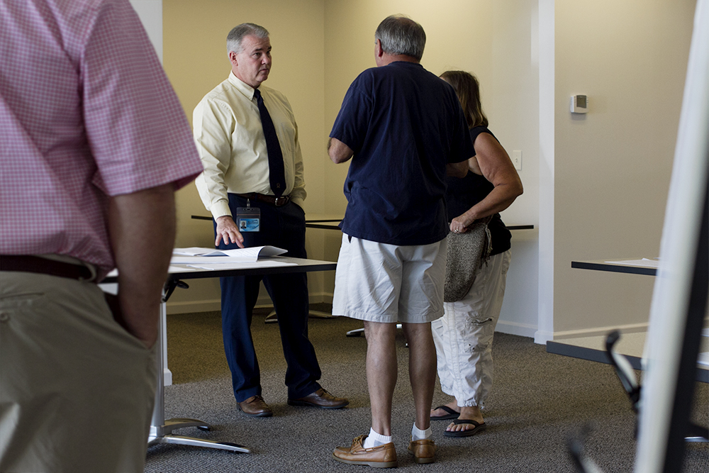 (Center) David Hollis speaks with Brunswick Forest property owners at a town-organized petition signing session Friday. The petition could potentially grant Brunswick Forest residents voting rights in H2GO's sanitary district, however, the agreement that would transfer utility service has not been inked or approved. (Port City Daily photo/Johanna Ferebee)