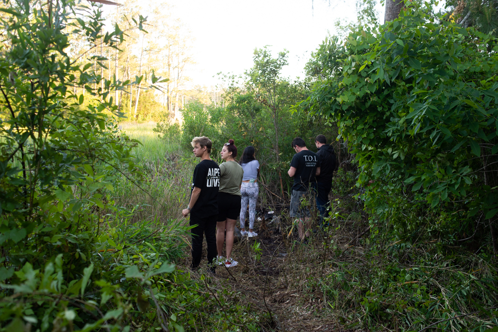 Friends of two women who were reported missing on April 15 inspect a marshy area where one of the woman’s car apparently landed. (Port City Daily photo/Mark Darrough)