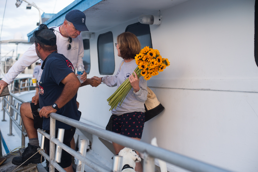 Kathy Davis shakes hands with Captain Dave Gardner as she boards the boat. The sunflowers will later be thrown into the ocean in honor of her son. (Port City Daily photo/Mark Darrough)