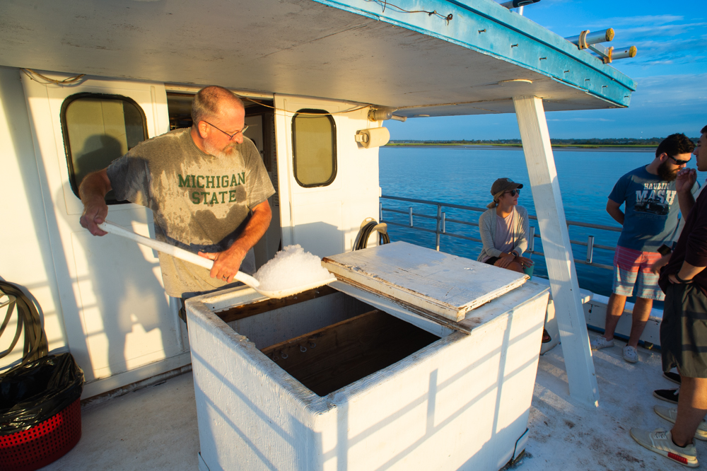 Crewmember Michael "Ski" Kowalski shovels ice for the cooler. (Port City Daily photo/Mark Darrough)