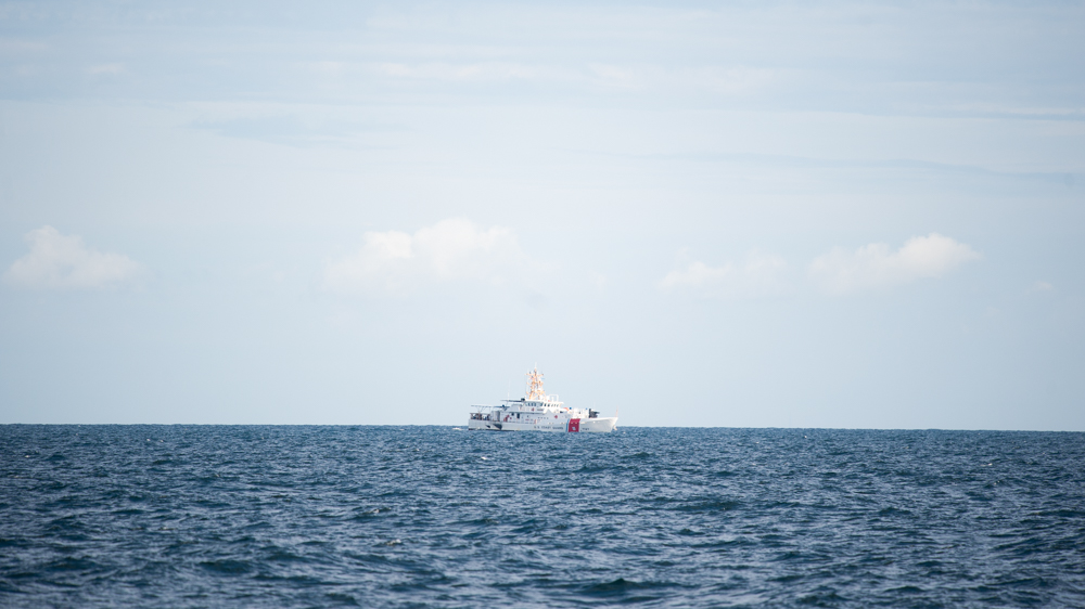 A U.S. Coast Guard ship watches the sinking operation of one of the branch's decommissioned boats from a distance. (Port City Daily photo/Mark Darrough)
